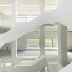 Wnętrze nowego muzeum sztuki nowoczesnej w Warszawie. Białe, geometryczne schody i przestrzenie tworzą nowoczesną architekturę.