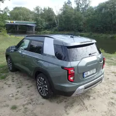 Zielony Torres auto zaparkowany nad rzeką, w tle most i las.