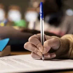 Dłoń pisze długopisem na papierze, przygotowując serdeczne życzenia po angielsku.