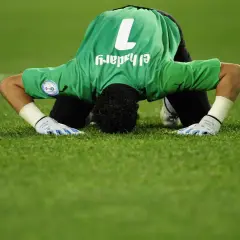 Bramkarz w zielonej koszulce z numerem 1, Essam El-Hadary, najstarszy piłkarz na mundialu, klęczy na murawie.