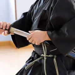 En person i svart dräkt håller ett samurajsvärd, en symbol för japanska krigare.