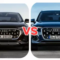 Dwa nowe Audi Q7 w zbliżeniu, czarne i granatowe, z napisem "VS" pośrodku.
