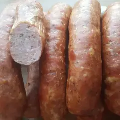 Kilka grubych, wędzonych kiełbas, jedna przekrojona, ukazująca mięsiste wnętrze. Idealne do grillowania, zastanawiasz się, ile parzyć kiełbasę wędzoną?