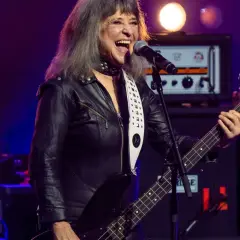 Suzi Quatro, w czarnej ramonesce, gra na basie i śpiewa. Ile lat ma Suzi Quatro? Wciąż pełna energii na scenie!