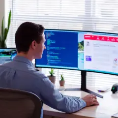 Uomo al lavoro, con la sua postazione schermo PC ottimale per la produttività.