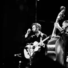 Julian Lage gra na gitarze akustycznej obok kontrabasisty na scenie.