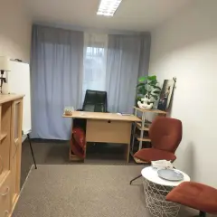 Gabinet psychologa: biurko, krzesło, rośliny, dwa fotele i stolik.