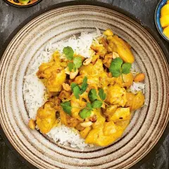 En krämig kycklingcurry med ris, toppad med koriander och jordnötter. En riktig curry nam nam!