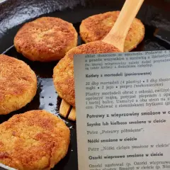 Złociste kotlety z mortadeli, usmażone na patelni, czekają na podanie z ziemniakami.