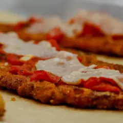 Escalopes de veau panées, garnies de sauce tomate et de mozzarella fondue, prêtes à être enfournées pour une délicieuse recette italienne parmigiana.