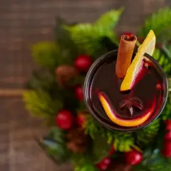 Glogg przepis: aromatyczny grzaniec z pomarańczą, cytryną i cynamonem, otoczony świątecznymi gałązkami.