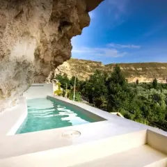 Piscina privada en cueva, ideal para una escapada fin de semana cerca de Madrid. Disfruta del paisaje verde y el cielo azul.
