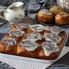 Deliciosos rollitos de canela recién horneados, cubiertos con un glaseado blanco cremoso, listos para ser disfrutados.