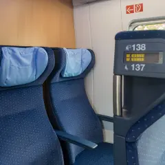 Blaue Sitze im Zug, mit Kopfkissen. Auf dem Display steht "Reserviert". Eine Reise durch Europa, vielleicht mit dem ICE.