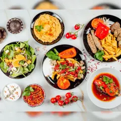 Mnóstwo pyszności na stole! Sałatka, hummus, pieczone warzywa, mięso i frytki – idealna zdrowa kolacja.