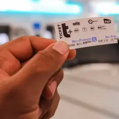 Main d'une personne tenant un ticket de métro parisien, prêt pour un voyage dans la ville.