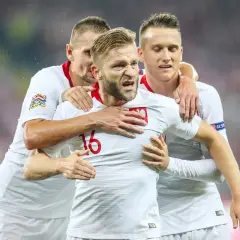 Trzech kapitanów reprezentacji Polski w białych strojach świętuje bramkę.