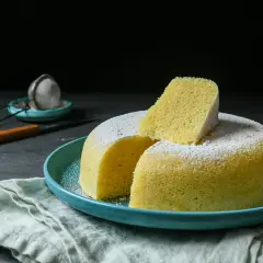 Delicioso bizcocho esponjoso, ideal para un mug cake yogur, espolvoreado con azúcar glas sobre un plato turquesa.