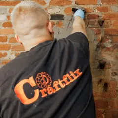Handwerker mit Handschuh trägt Mörtel auf beschädigtes Mauerwerk auf, um das Injektionsverfahren durchzuführen.