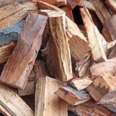 Stapel von gespaltenem Brennholz, bereit für den Kamin. Das Holz zeigt die Maserung und Rinde, die den hohen Brennwert beeinflussen.