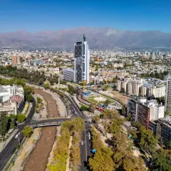 Widok na nowoczesną architekturę i rzekę w Santiago, stolicy Chile, z górami w tle.