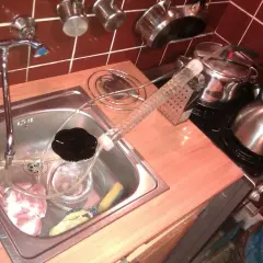 Zlew z kranem, w nim mięso i szklana rurka. Obok garnek i czajnik. To początek, jak zrobić zacier.