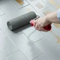 Rullo applica vernice grigia su piastrelle del pavimento. Ottime opinioni per dipingere piastrelle pavimento.
