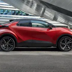 Nowoczesna, czerwona Toyota plug-in na tle futurystycznego budynku. Stylowy design i ekologiczna jazda.