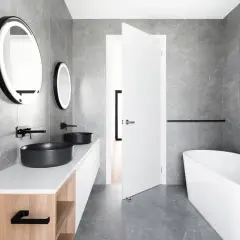 Nowoczesne lustro łazienkowe loft z podświetleniem, nad dwoma czarnymi umywalkami nablatowymi.