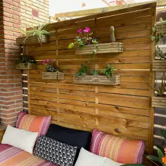 Un rincón acogedor con cojines coloridos y una pared de madera con macetas colgantes, perfecta para tu **diy decoracion** exterior.