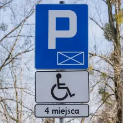 Znak P z kopertą i symbolem wózka inwalidzkiego, informujący o 4 miejscach parkingowych dla niepełnosprawnych.
