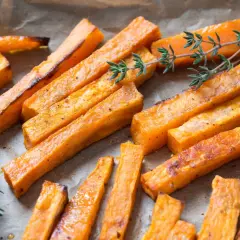 Boniato air fryer crujiente, cortado en bastones y espolvoreado con hierbas frescas.