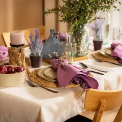 Elegancka, codzienna dekoracja stołu w salonie z fioletowymi serwetkami, świecą i lawendą.