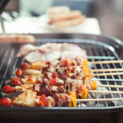 Fleischspieße mit Gemüse brutzeln auf einem Grill. Ein gemütliches Grillen in der Wohnung, auch bei schlechtem Wetter.