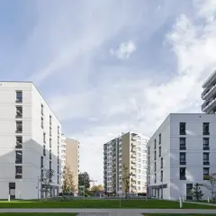 Nowoczesne bloki mieszkalne z balkonami i zielonym dziedzińcem.