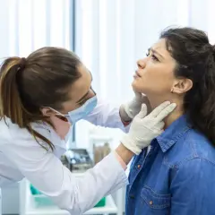 Lekarz od tarczycy bada szyję pacjentki.