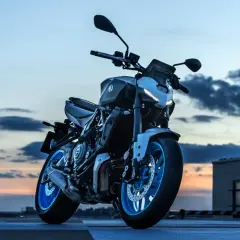Yamaha MT-07 gotowy do nocnej jazdy. Niebieskie felgi lśnią w blasku zachodzącego słońca.