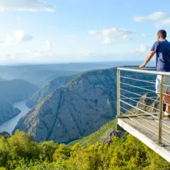 Hombre en el mirador de Cabezoas, contemplando un cañón con un río serpenteante y montañas cubiertas de vegetación.