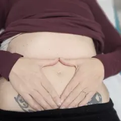 Manos sobre el abdomen, sintiendo el dolor de espalda por gases.