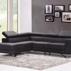 Divano angolare in pelle grigio antracite scuro, con tappeto soffice e cornici decorative alle pareti.