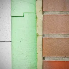 Warstwa izolacyjna ze styroduru pod drzwi wejściowe, obok ceglanej ściany.