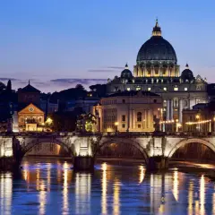 Un suggestivo ponte a Roma illumina il Tevere al crepuscolo, con San Pietro sullo sfondo.