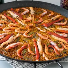 Paella gigante con gambas y pimientos rojos, perfecta para compartir. Cada porción de arroz está llena de sabor.