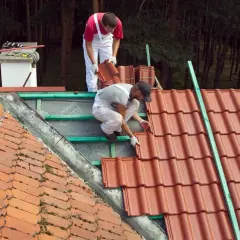 Dwóch dekarzy układa nowe dachówki. Zastanawiasz się, ile za położenie dachówki?