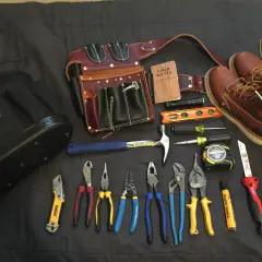 Un cinturón de cuero con múltiples compartimentos, un martillo, alicates, destornilladores, cinta métrica y botas de trabajo. Todo listo para un electricista.