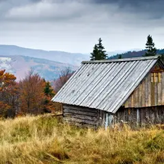 Drewniana chata na mędralowa szlak, otoczona jesienną przyrodą i pagórkami.