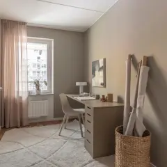 Mysigt hemmakontor med skrivbord, stol, matta och rullar av tyg. Perfekt hemmakontor inspiration för kreativa själar.