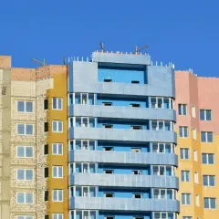 Kolorowy blok mieszkalny w budowie. Zastanawiasz się nad wykupem mieszkania komunalnego? Cena za metr może być kluczowa.