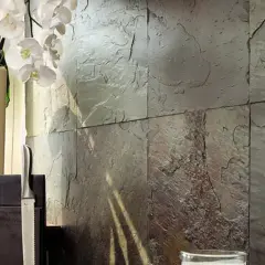 Kamienna ściana z łupków kamiennych, ozdobiona białymi orchideami i eleganckimi nożami.