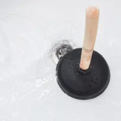 Ventouse sur un drain de baignoire avec de l'eau qui coule. Une solution simple pour savoir comment déboucher une baignoire rapidement.